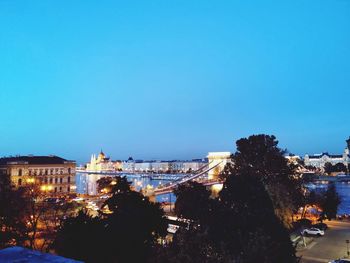 Illuminated buildings against blue sky at dusk