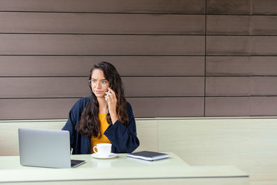 Young woman using mobile phone on table