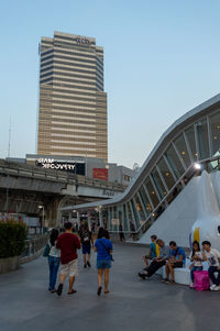 People walking on modern building against sky in city