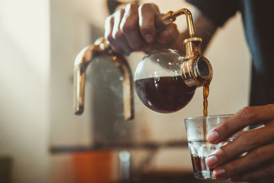 Close-up of hand pouring wine in glass