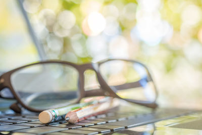 Close-up of eyeglasses and pencils on laptop