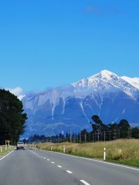 Road by mountains against blue sky