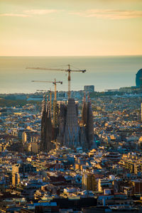 Aerial view of buildings by sea against sky during sunset