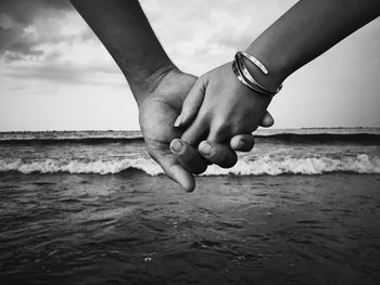 Close-up of hands holding sea against sky grayscale