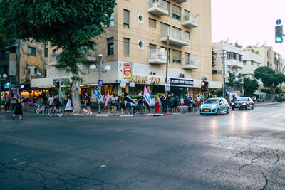 People on road against buildings in city