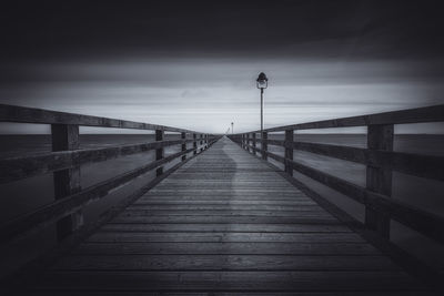 Pier on footbridge against sky