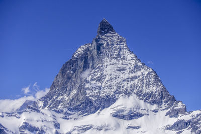 Low angle view of snowcapped mountain against blue sky