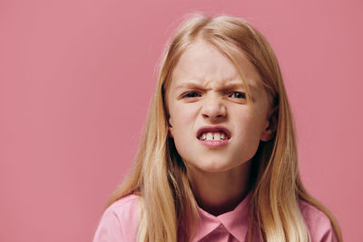 Close-up of young woman against pink background