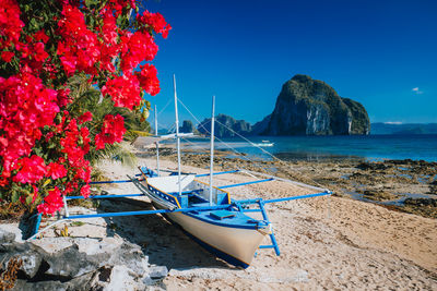 Boats moored at sea shore against blue sky