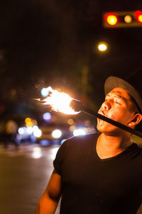 Fire-eater blowing fire on street at night