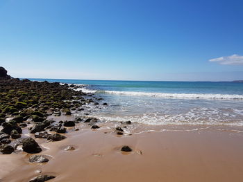 Scenic view of beach against clear blue sky