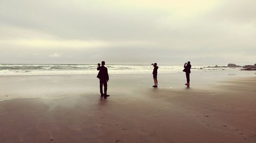 Three people photographing on beach