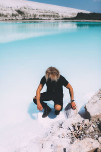 Rear view of woman on rock in sea