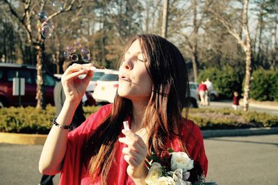 Woman with eyes closed blowing bubbles while standing on street