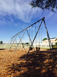 Row of swings in playground against sky