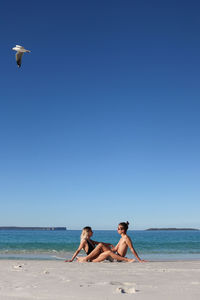 Lovely couple in black bikini and beige swimsuit on the beach in eastern australia with an eagle 