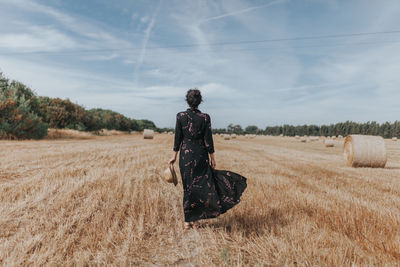 Rear view of woman on agricultural field against sky