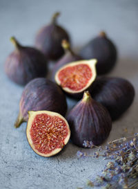 Fig fruits, whole and halves, and a branch of lavender on a gray background