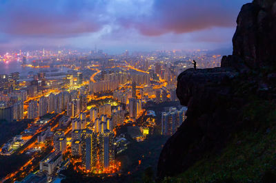 Illuminated buildings in city against cloudy sky