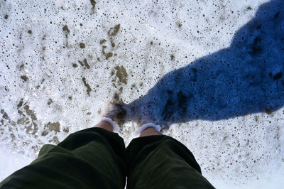 Low section of man standing in sea