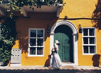 Full length of a woman outside house against building