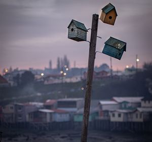 Close-up of illuminated street light against buildings at sunset