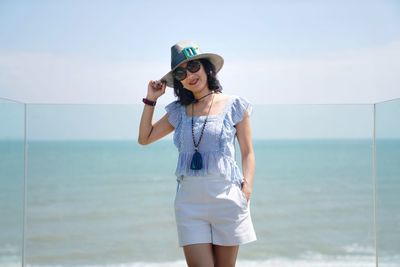 Young woman standing by sea against sky