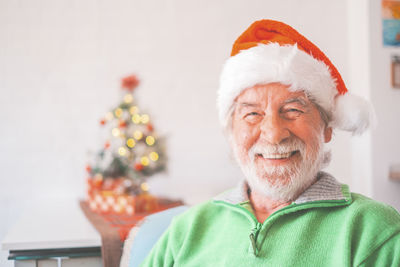 Portrait of smiling senior man wearing santa hat at home