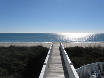 Empty white wooden footpath towards sea