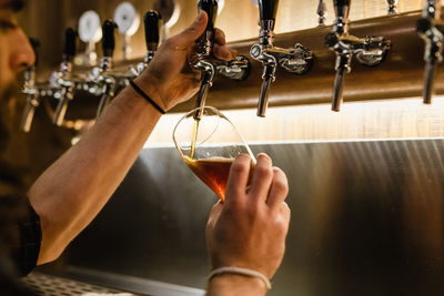 Cropped hands of bartender filling beer glass at bar