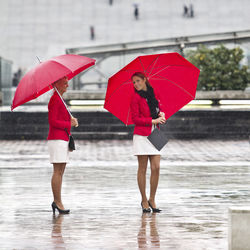 Full length of woman with umbrella standing in water