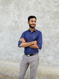 Portrait of young man standing against wall