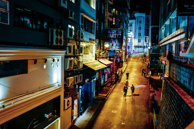 High angle view of illuminated street amidst buildings in city at night