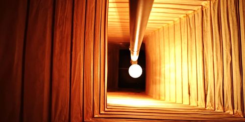 Illuminated light bulbs hanging from ceiling of building