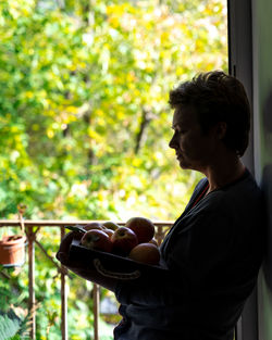 Side view of young man holding food outdoors