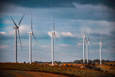 Windmills on field against sky