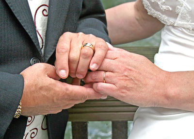Midsection of bride and groom holding hands