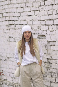 Portrait of smiling young woman standing against brick wall