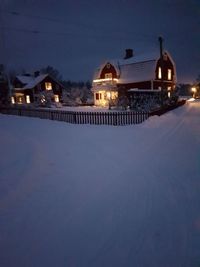 Illuminated houses against sky at night during winter