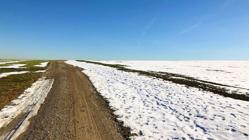 Scenic view of snow covered land against clear blue sky