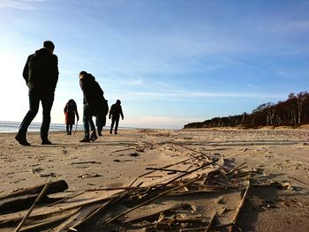 Rear view of people walking at beach against sky