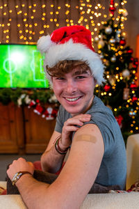Portrait of a young male smiling after getting a vaccine - man showing her arm with bandaid