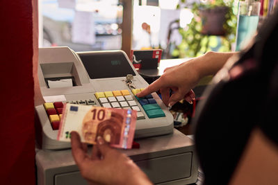 A hairdresser puts her money in her cash register. small business