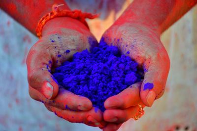 Midsection of person holding blue powder paint