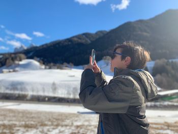 Man holding smart phone while standing on snow covered mountain