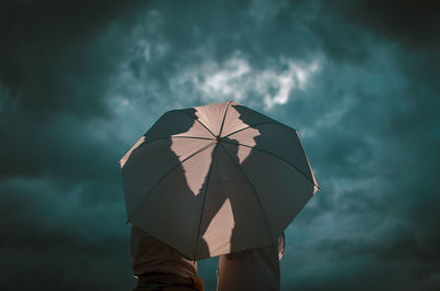 Low angle view of man holding umbrella against sky