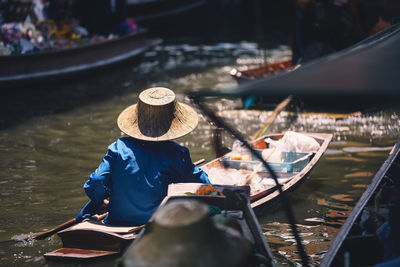 Selective focus on traditional hat of vendor on water at thai floating market. 