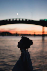 Silhouette woman standing at sea against sky during sunset