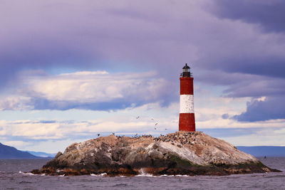 Lighthouse by sea against sky