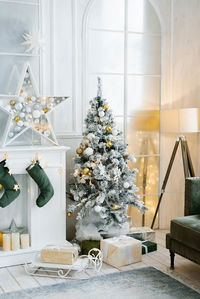 Elegant beautiful silver christmas tree with white and gold balloons in the classic living room